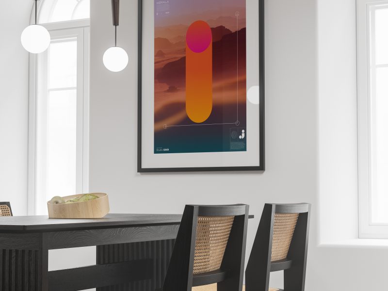 A modern dining room with a large abstract artwork on the wall, featuring a vibrant orange gradient. The room has a black table, four chairs with woven seats, and twin hanging lights.